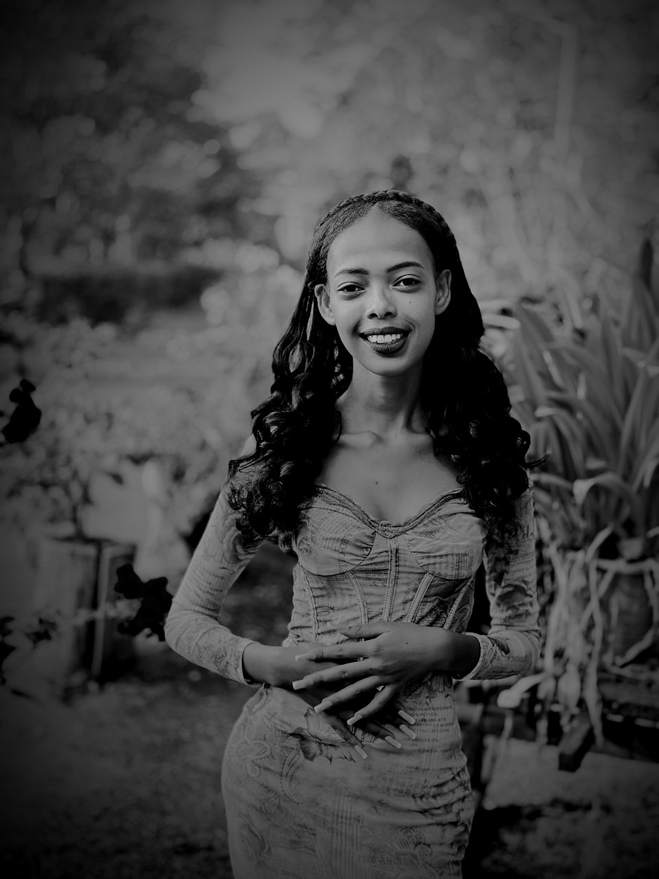 Amen, the Afrofeast brand ambassador, in a peach dress with long dark curls, standing among flowers in the Royal Gardens, Siem Reap, Cambodia