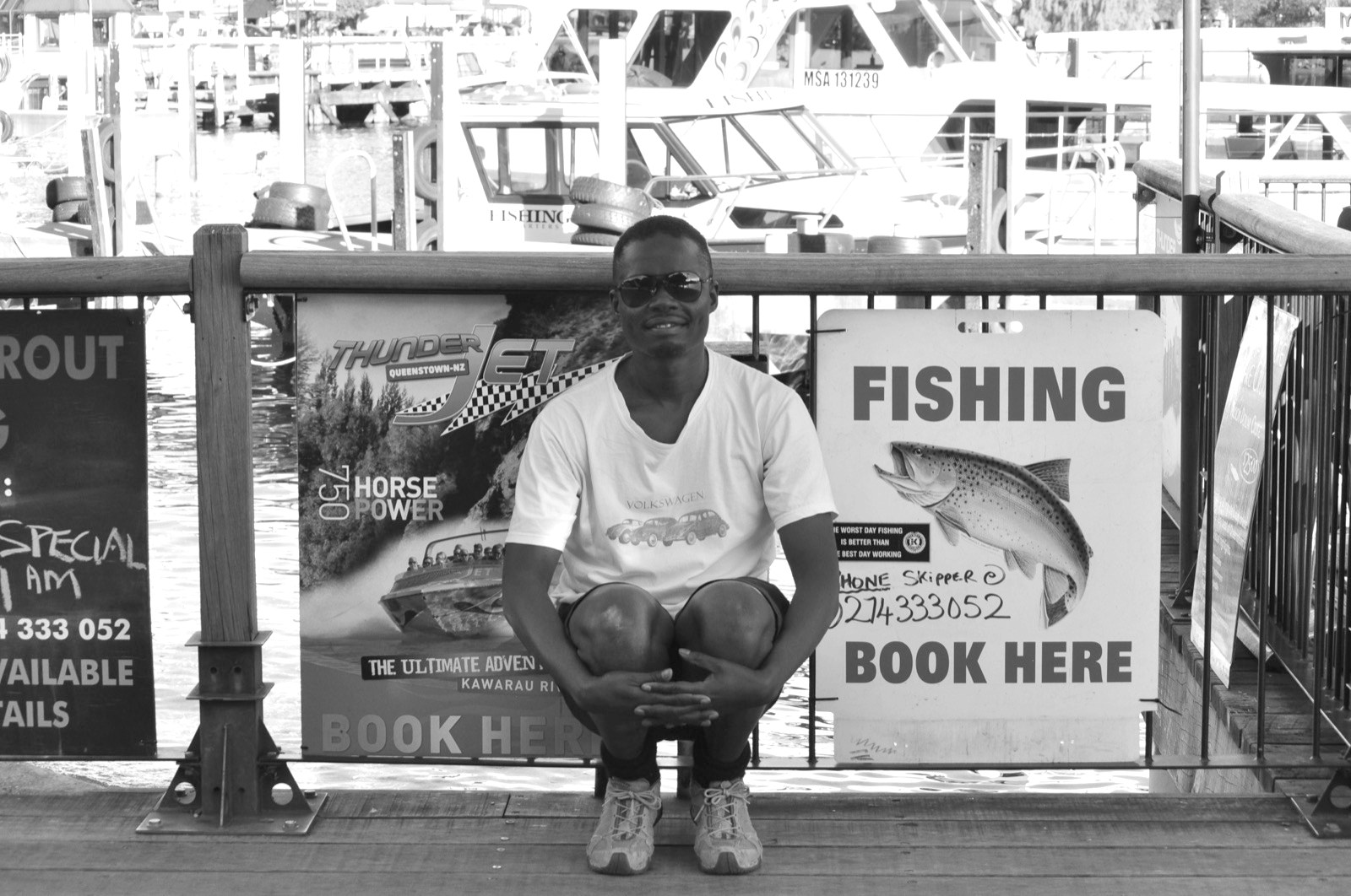 Dennis Obel sitting by the fishing and jet-boat charters at the Queenstown marina, Lake Wakatipu, New Zealand